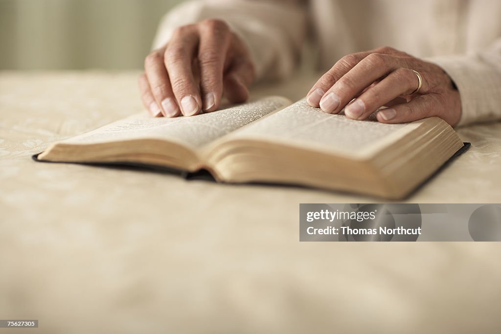 Senior man reading Bible, close-up of hands