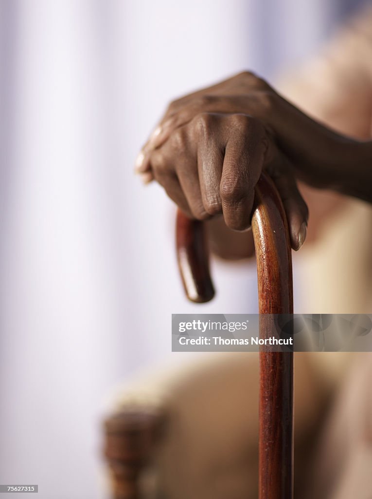 Senior woman holding cane, close-up of hands