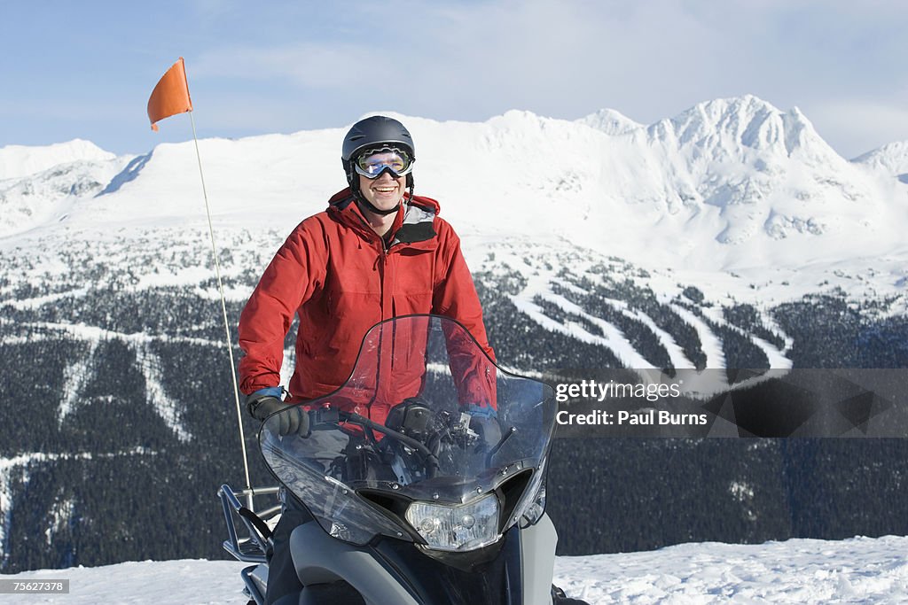 Snow patrol rescue worker riding snowmobile, mountains in background