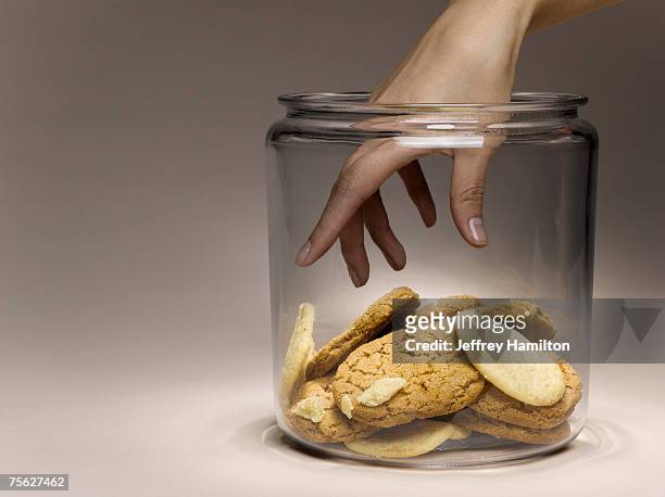 woman reaching for cookies in cookie jar, close-up of hand - cookie jar stock pictures, royalty-free photos & images