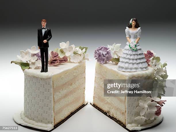 bride and groom figurines standing on two separated slices of wedding cake - hochzeitstorte stock-fotos und bilder