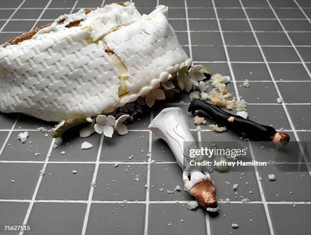 bride and groom figurines lying at destroyed wedding cake on tiled floor - gebrochen stock-fotos und bilder