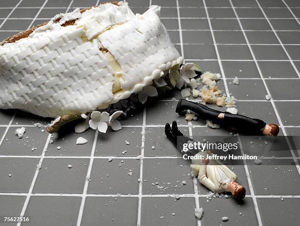 two groom figurines lying at destroyed wedding cake on tiled floor - kuchenboden stock-fotos und bilder
