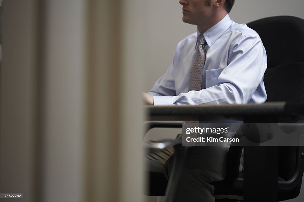 Man sitting in office chair, mid section