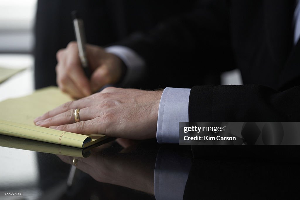 Businessman writing in notebook, close-up of hands