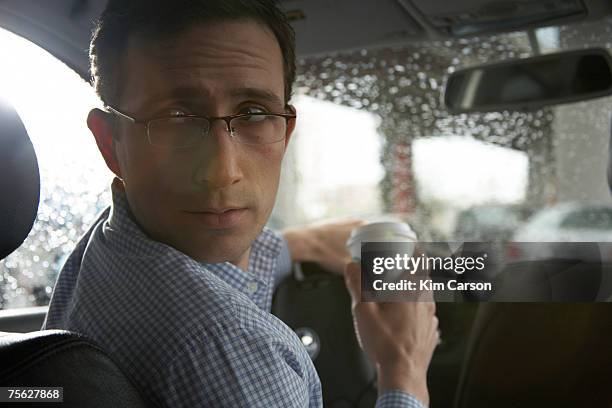man drinking coffee while driving car, looking over shoulder - ongeduldig stockfoto's en -beelden