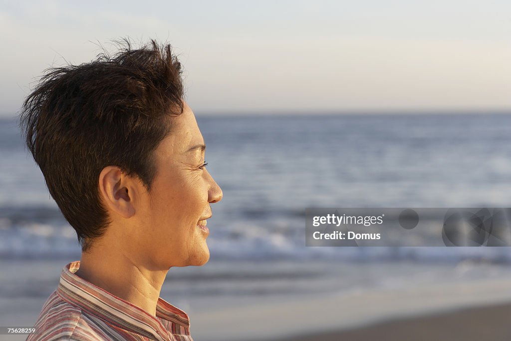 Mature woman on beach, smiling, profile, head and shoulders