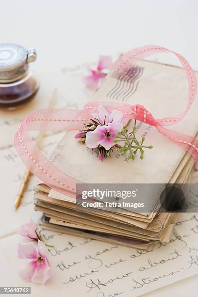 stack of old letters next to flowers and ink bottle - carta de amor fotografías e imágenes de stock