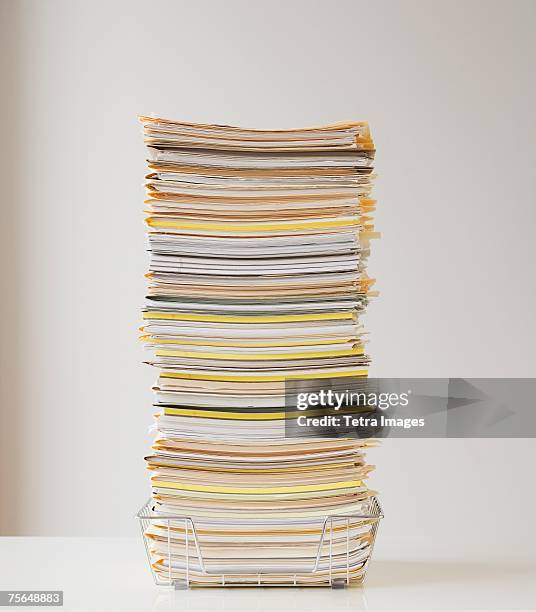 large stack of paperwork in wire basket - bürokratie stock-fotos und bilder