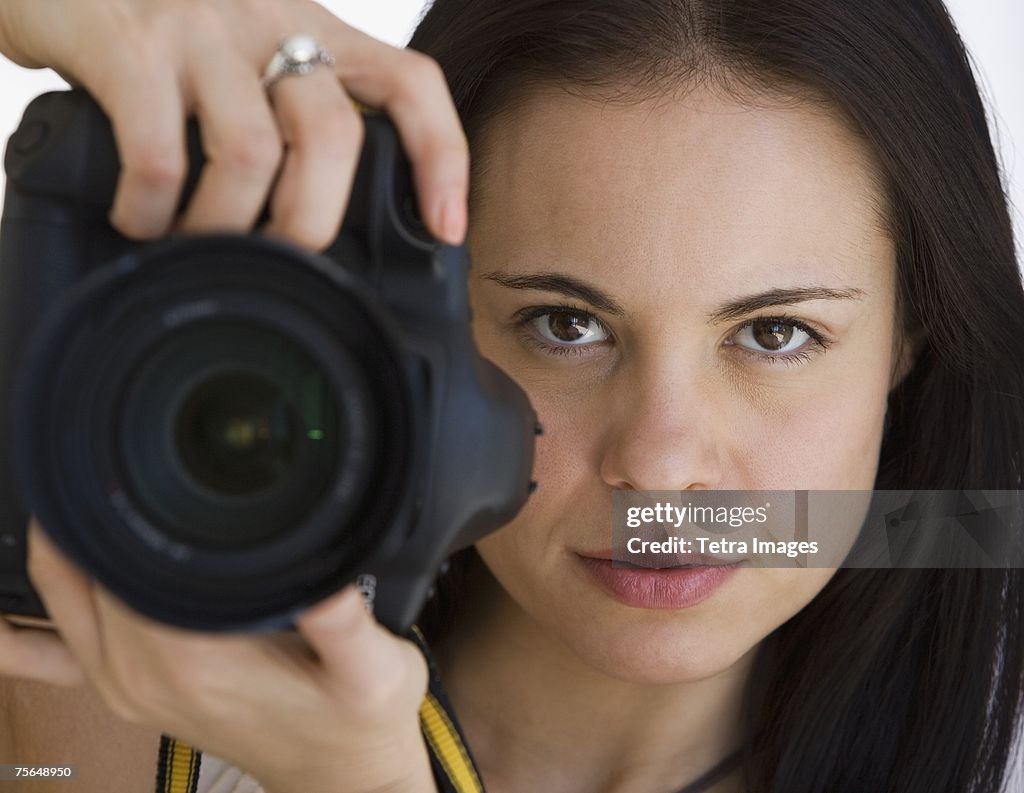 Woman holding camera next to face