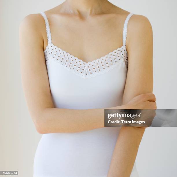 woman with arm crossed over torso - corpetto foto e immagini stock