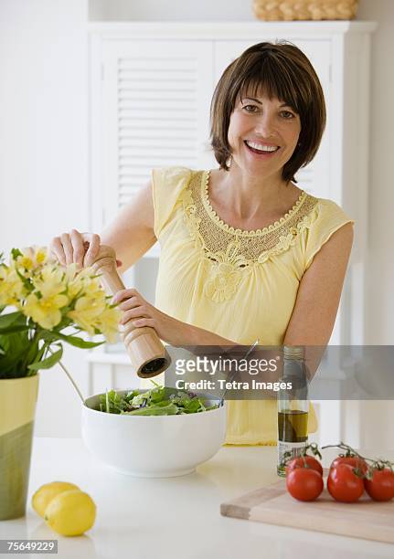 woman grinding pepper onto salad - pepper mill stockfoto's en -beelden