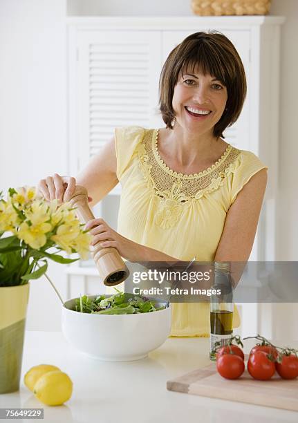 woman grinding pepper onto salad - pepper mill stock pictures, royalty-free photos & images