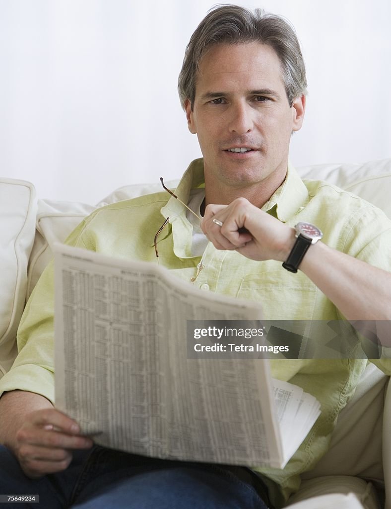 Man holding newspaper on sofa