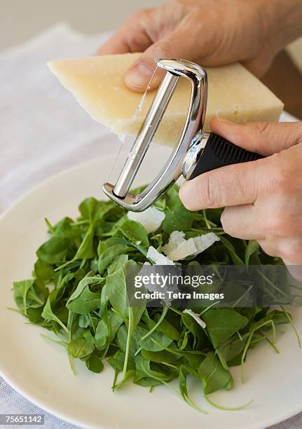 man shaving cheese onto salad - hombre cortando queso fotografías e imágenes de stock