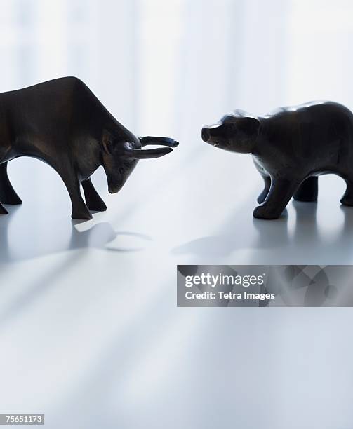 bear and bull figurines facing each other - bull bear stock pictures, royalty-free photos & images