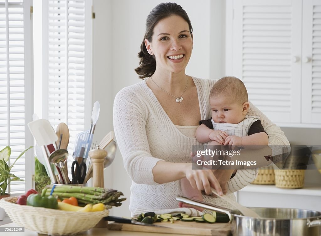 Mother holding baby and cooking