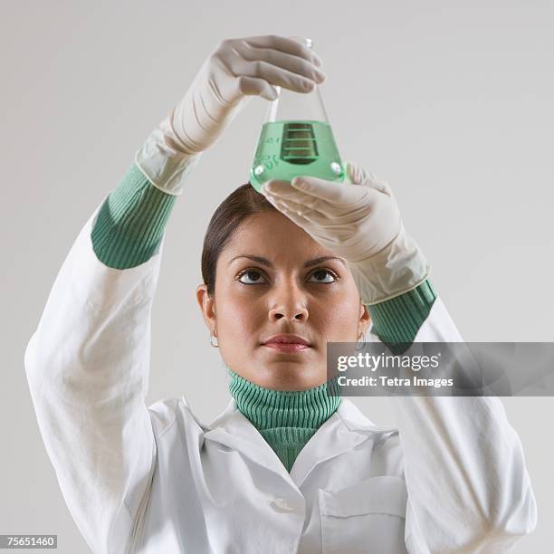 indian female scientist looking at beaker of liquid - beaker white background stock pictures, royalty-free photos & images