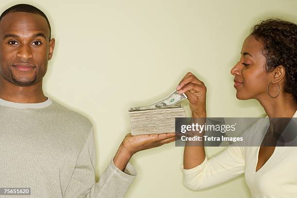 woman taking money from stack in husband's hand - african american woman with money stock-fotos und bilder