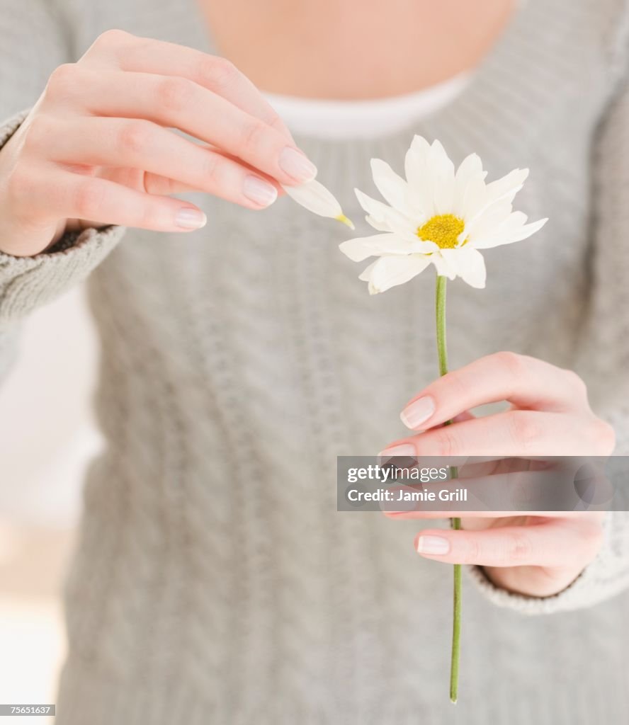 Woman pulling petal off flower