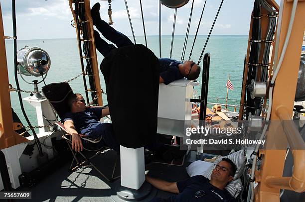 With the boat's air conditioner broken crew members Nick McDole, left, Dan Finke and David Singleton all try to catch up on sleep on the open bridge...