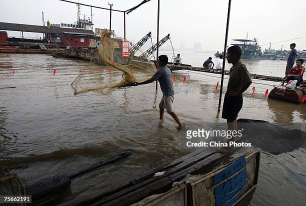 People fish in front of a store inundated by floodwaters on the shore of the Yangtze River, on July 25, 2007 in Wuhan of Hubei Province, central...