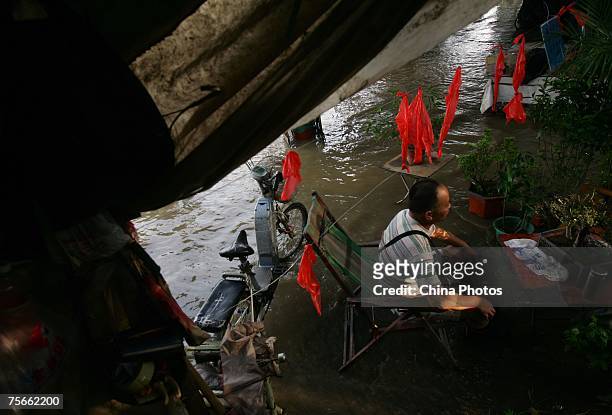 Man sits in front of a store inundated by floodwaters on the shore of the Yangtze River, on July 25, 2007 in Wuhan of Hubei Province, central China....