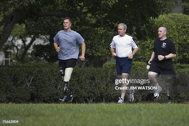 President George W. Bush jogs with US Army Sergeant Neil Duncan and US Army Specialist Max Ramsey on the South Lawn of the White House in Washington,...