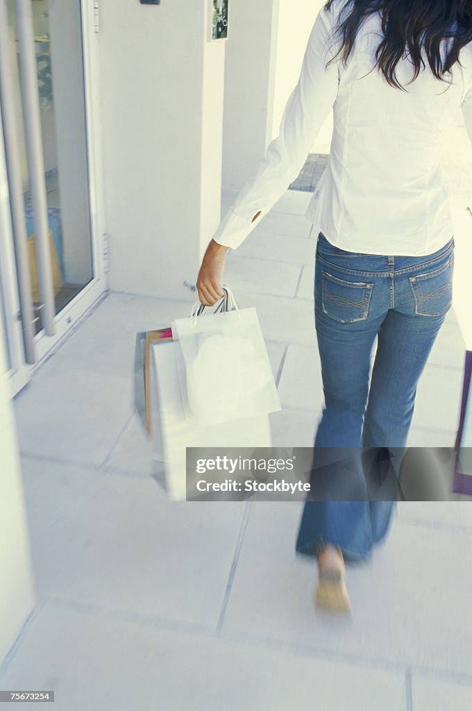 Young woman walking with shopping bags, rear view, elevated view