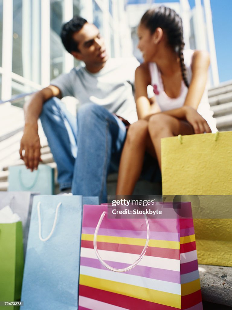 Young couple sitting on steps with shopping bag