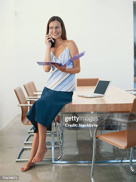 woman sitting on conference table holding file, using mobile phone - 幼吊帶 個照片及圖片檔