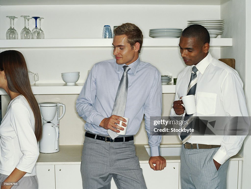 Two businessmen with coffee cup looking at woman
