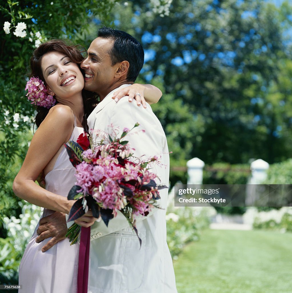 Groom and bride embracing on lawn, smiling