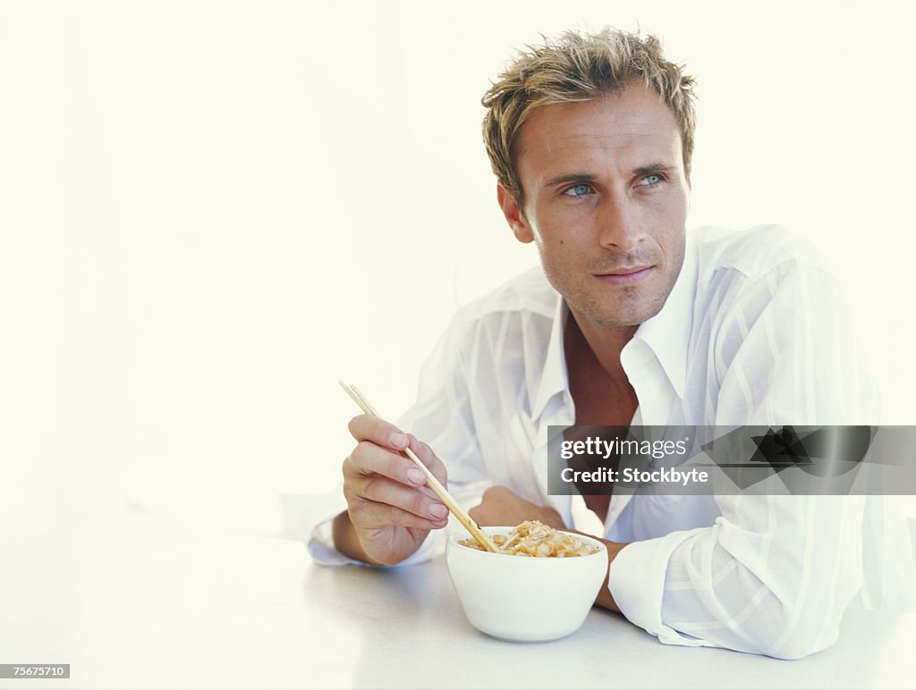 Young man eating noodles, close-up