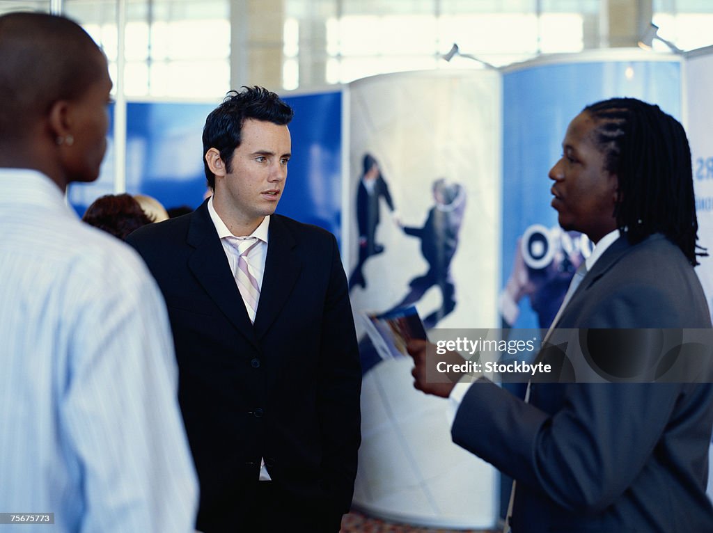 Businesswoman talking with men at exhibition