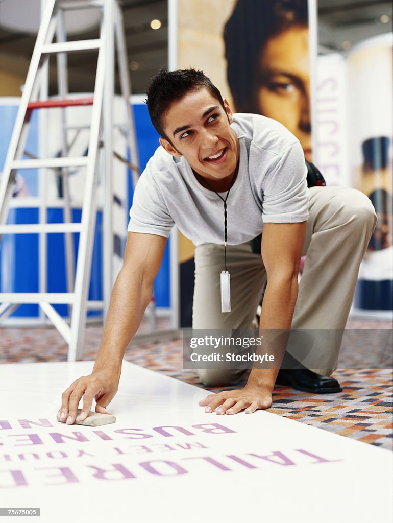 Young man wiping banner, looking away, smiling