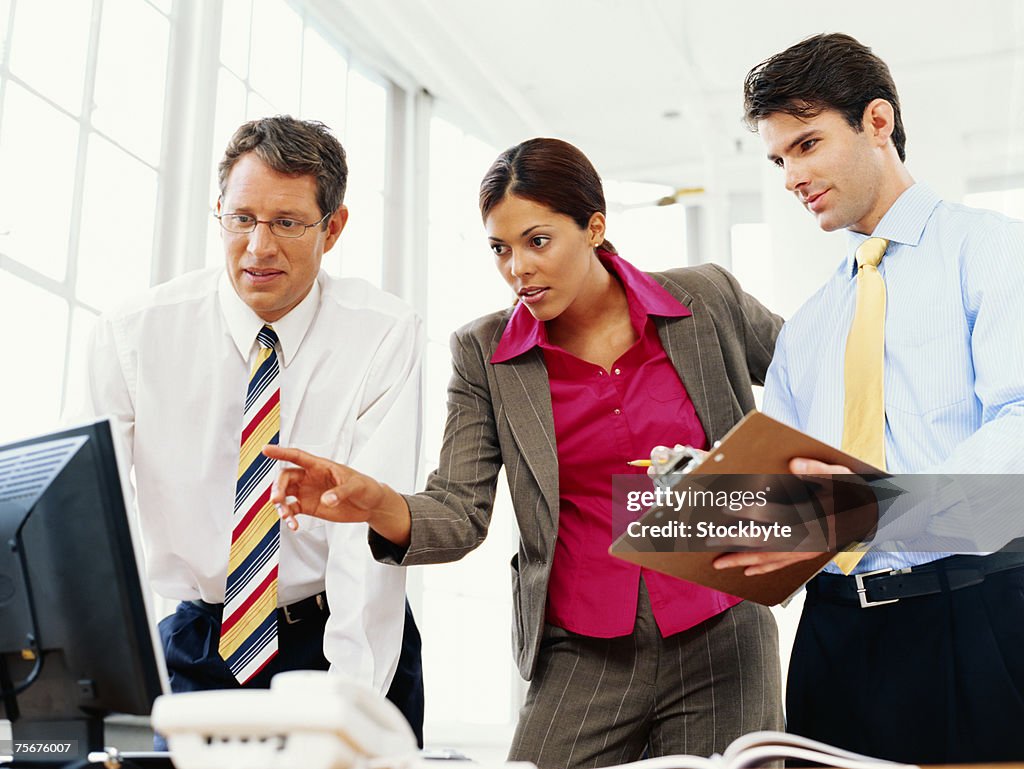 Businessmen and businesswoman using computer, low angle view