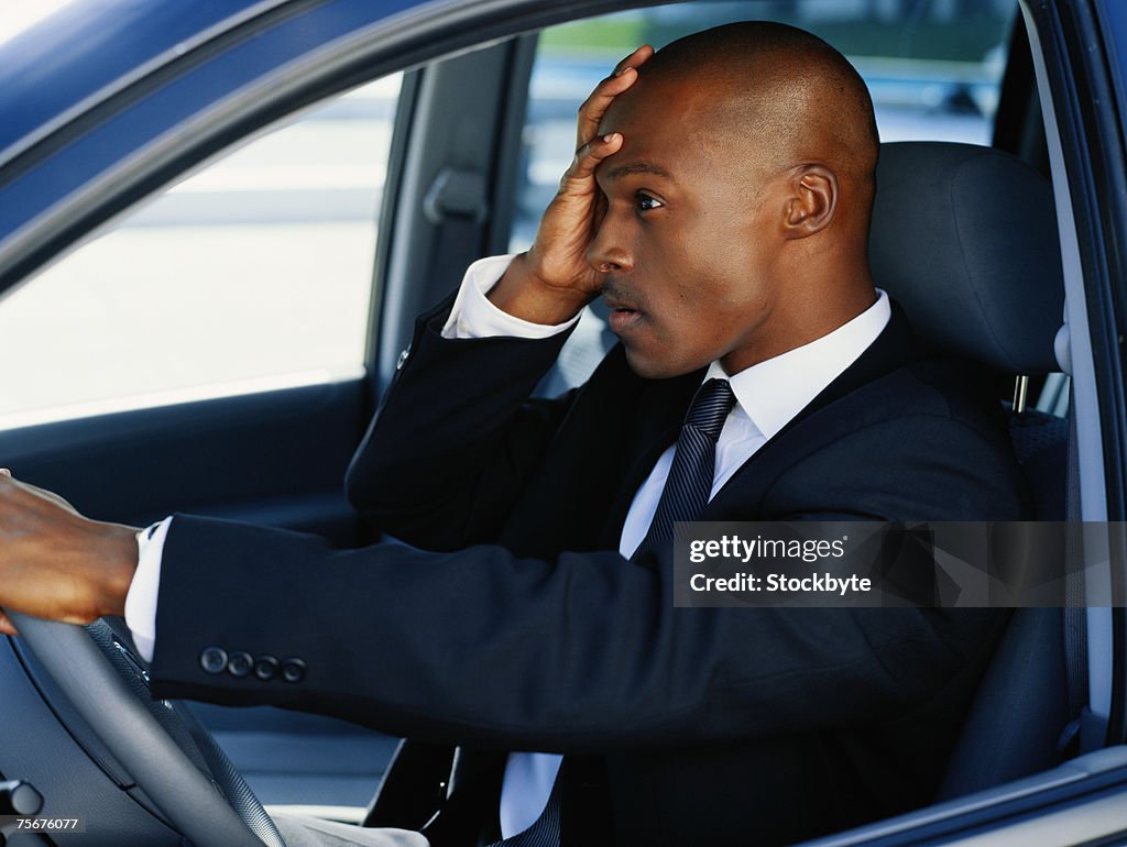 Businessman sitting in car with head in hands