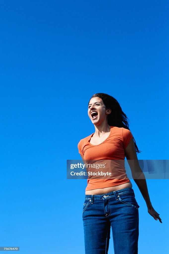 Young woman jumping, low angle view