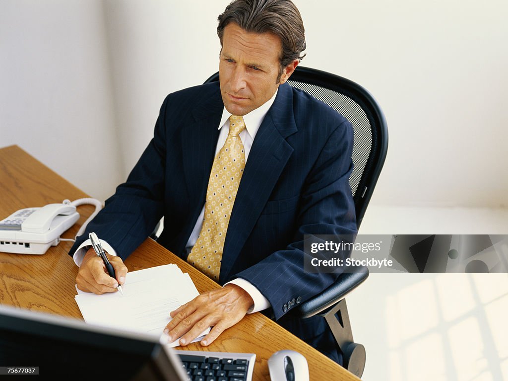 Businessman sitting at desk and writing, elevated view