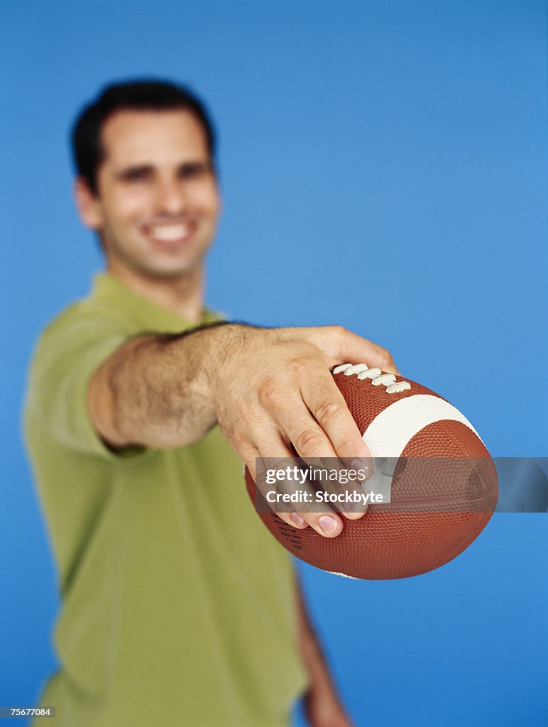 Man holding rugby ball, focus on ball, close-up