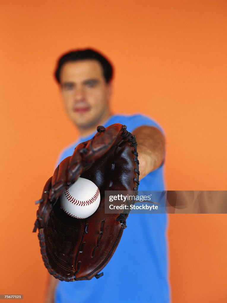 Man holding baseball in baseball glove, focus on ball, close-up