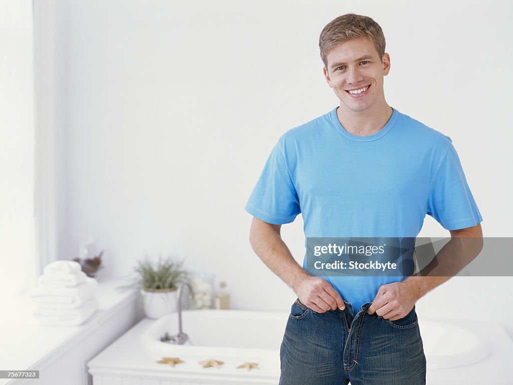Young man getting dressed, smiling, portrait