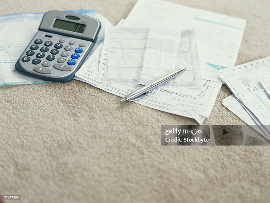 Calculator and ballpoint pen on bills