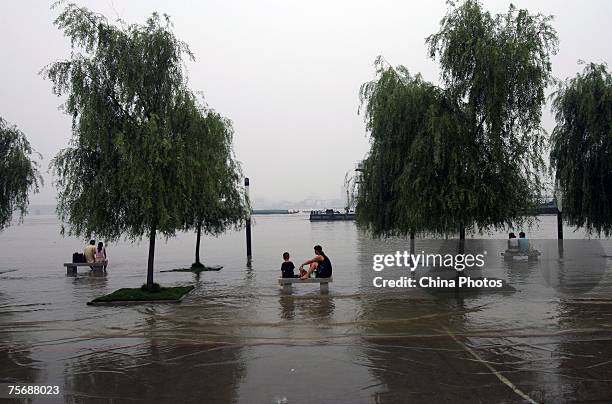 People sit on stone stools in an area inundated by floodwaters on the shores of the Yangtze River July 26, 2007 in Wuhan of Hubei Province, central...