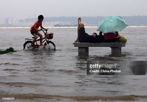 Boy pedals past a stone stool in an area inundated by floodwaters on the shores of the Yangtze River July 26, 2007 in Wuhan of Hubei Province,...