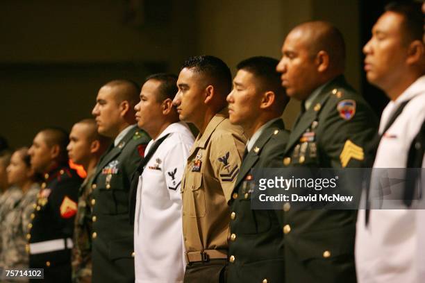Members of the US military rise to be honored for their service by the presiding judge after being sworn in as US citizens during naturalization...