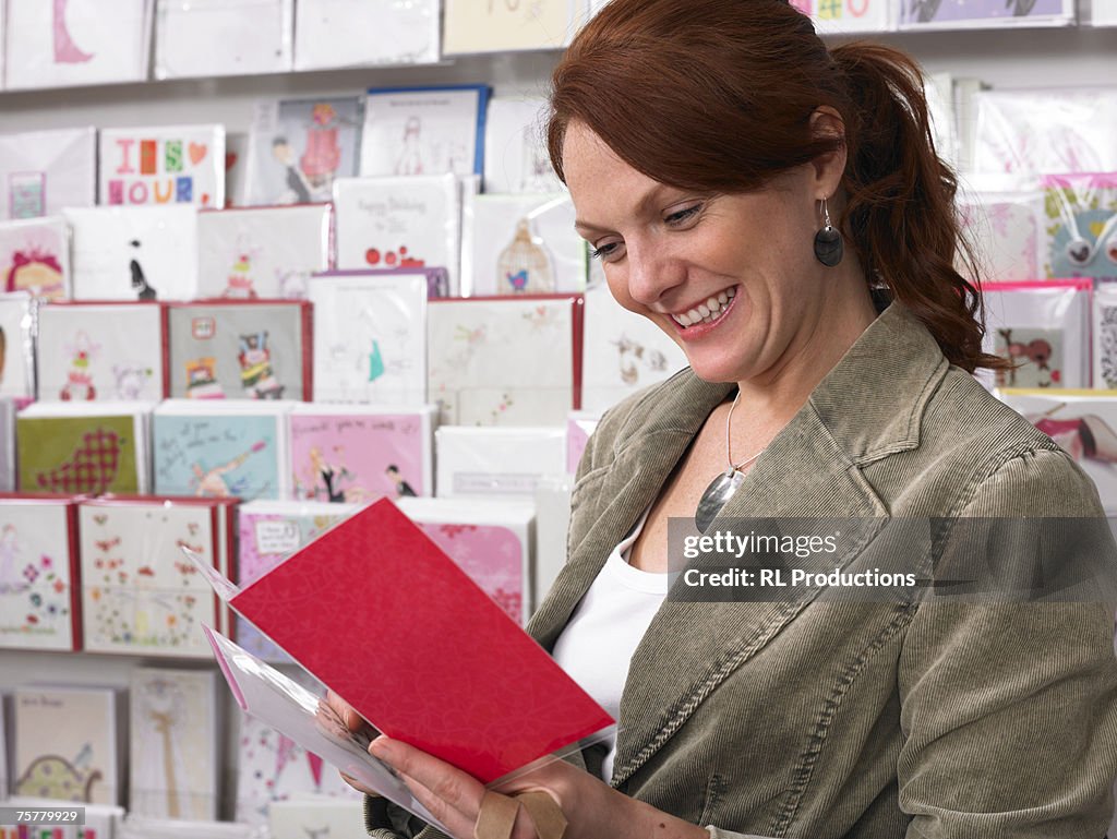 Young woman looking at greeting card from rack, side view