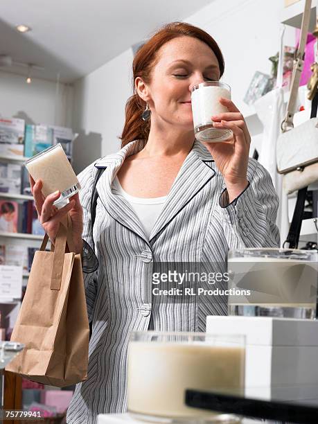 young woman in gift shop, sniffing candles, eyes closed, smiling - scented candle stock pictures, royalty-free photos & images