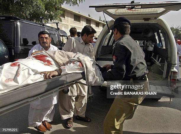 Pakistani officials shift the body of Baluchistan provincial spokesman, Raziq Bugti into an ambulance after gunmen shot him dead in Quetta, 27 July...